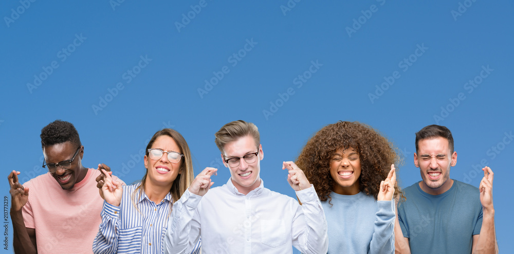 Composition of group of friends over blue blackground smiling crossing fingers with hope and eyes closed. Luck and superstitious concept. Composition of group of friends over blue blackground smiling crossing fingers with hope and eyes closed. Luck and superstitious concept.