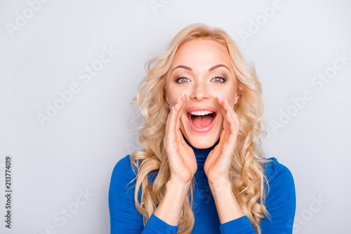 Portrait of pretty, trendy, charming, lovely, nice, sexy, cute, blonde woman in blue turtleneck isolated on grey background cover wide open mouth with two palm calling someone photo