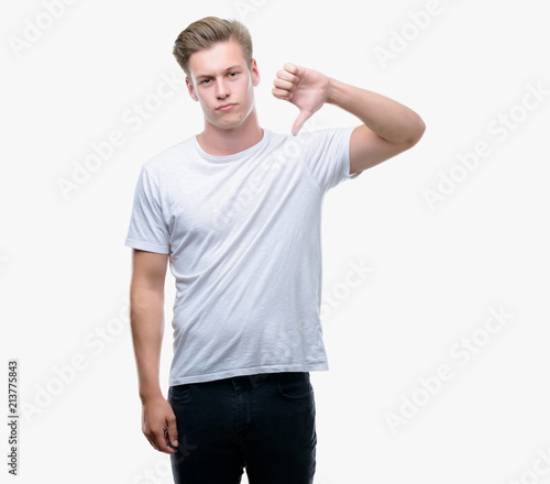 Young handsome blond man with angry face, negative sign showing dislike with thumbs down, rejection concept