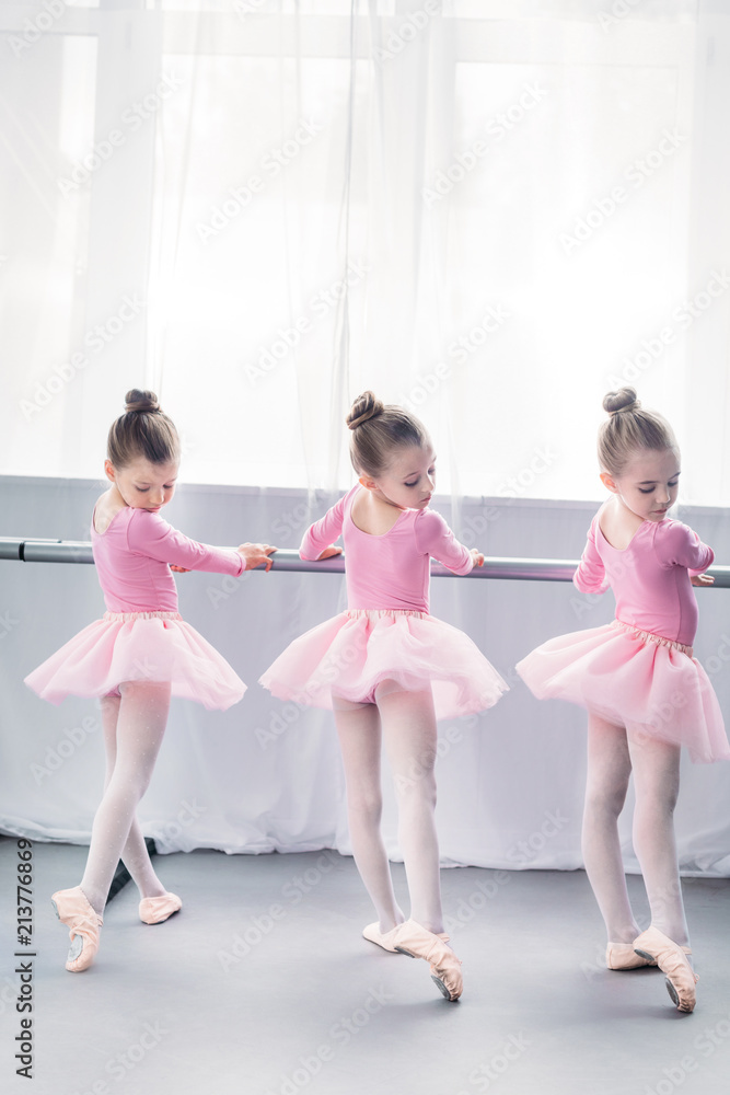 Naklejka premium back view of graceful little ballerinas practicing ballet in studio