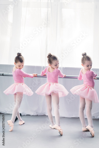 back view of graceful little ballerinas practicing ballet in studio