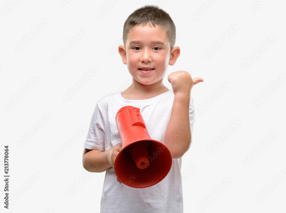 Dark haired little child holding megaphone pointing with hand and finger up with happy face smiling Dark haired little child holding megaphone pointing with hand and finger up with happy face smiling