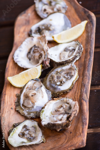 Oysters with lemon on wooden plate.