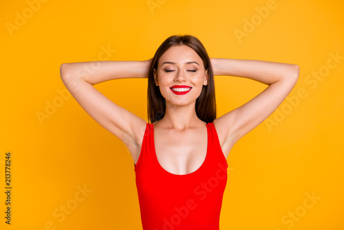 Time to rest from work on summer holiday! Close up portrait of girl who dreams about vacation holding her hands behind her head isolated on vivid yellow background