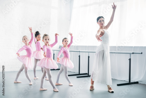 young teacher practicing ballet with adorable kids in pink tutu skirts
