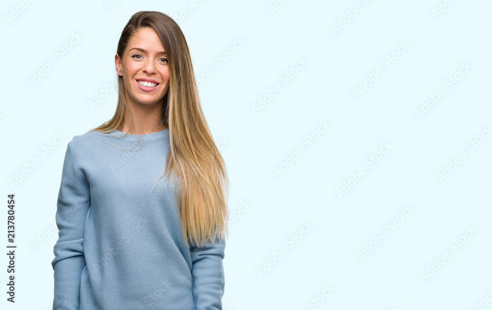 Beautiful young woman wearing sweater and jeans with a happy face standing and smiling with a confident smile showing teeth Beautiful young woman wearing sweater and jeans with a happy face standing and smiling with a confident smile showing teeth