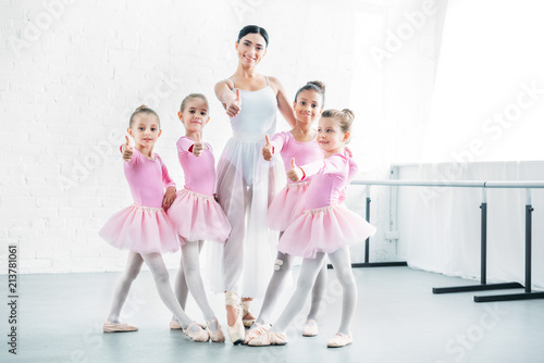 Fotografija little ballerinas and ballet teacher showing thumbs up and smiling at camera in