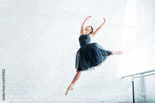 Fototapeta Naklejka Na Ścianę i Meble -  low angle view of beautiful young ballerina dancing in ballet studio