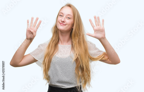 Blonde teenager woman wearing moles shirt showing and pointing up with fingers number nine while smiling confident and happy.