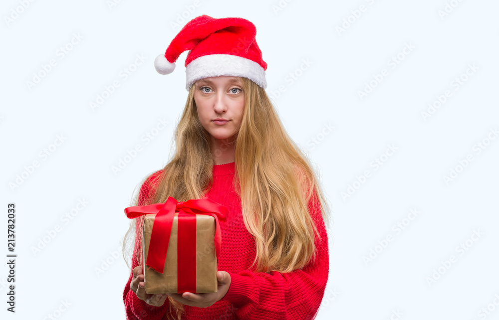 Blonde teenager woman wearing santa claus hat with a confident expression on smart face thinking serious Blonde teenager woman wearing santa claus hat with a confident expression on smart face thinking serious