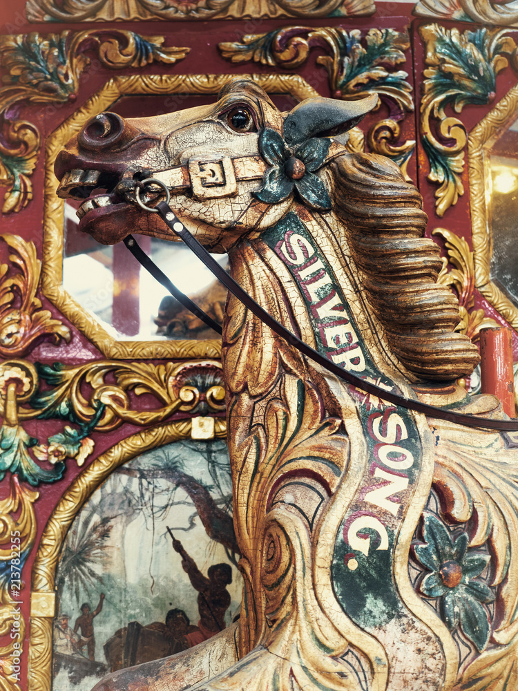 head shot of vintage wooden horse from carousel funfair ride,with painted panels in background