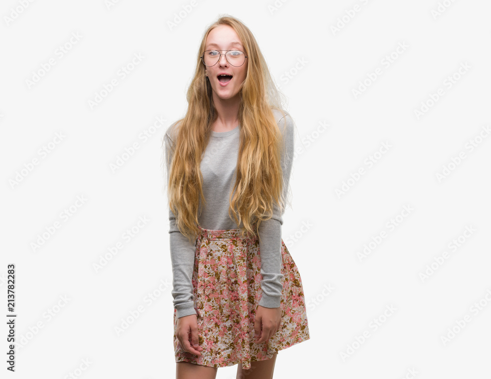 Blonde teenager woman wearing flowers skirt afraid and shocked with surprise expression, fear and excited face. Blonde teenager woman wearing flowers skirt afraid and shocked with surprise expression, fear and excited face.