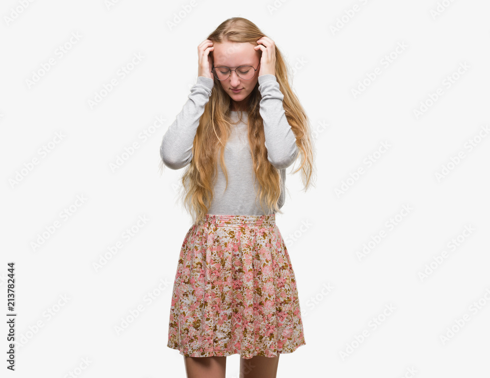 Blonde teenager woman wearing flowers skirt with hand on head for pain in head because stress. Suffering migraine. Blonde teenager woman wearing flowers skirt with hand on head for pain in head because stress. Suffering migraine.