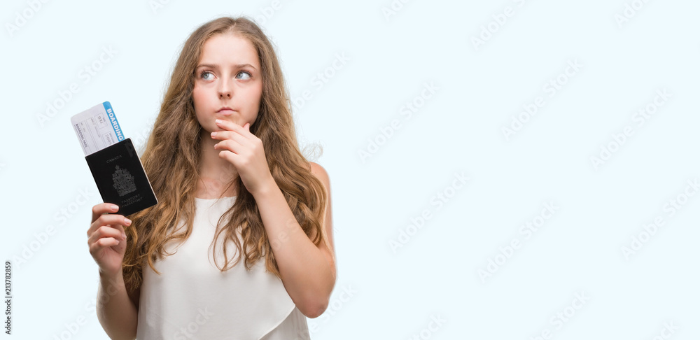 Young blonde woman holding passport of canada and boarding pass serious face thinking about question, very confused idea Young blonde woman holding passport of canada and boarding pass serious face thinking about question, very confused idea