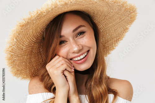 Photo of attractive woman 20s wearing big straw hat looking at camera with happy smile, isolated over white background