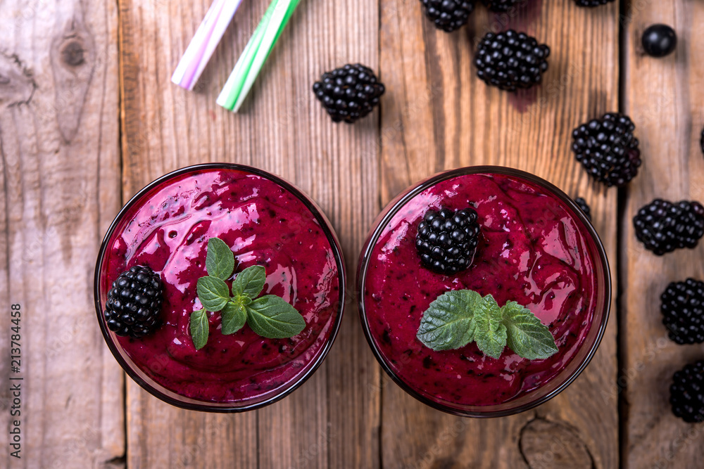 Blackberry natural smoothie with mint and fresh berries in glasses on a wooden background, top view Blackberry natural smoothie with mint and fresh berries in glasses on a wooden background, top view