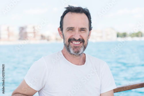Handsome senior man traveling on sailboat and smiling happy and confident