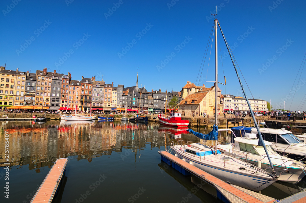 HONFLEUR, FRANCE-MAY 05, 2018: Yachts in the Honfleur harbor in a spring day. Color houses and their reflection in water. Ancient The Lieutenancy Building  (Fr: La Lieutenance) at the background