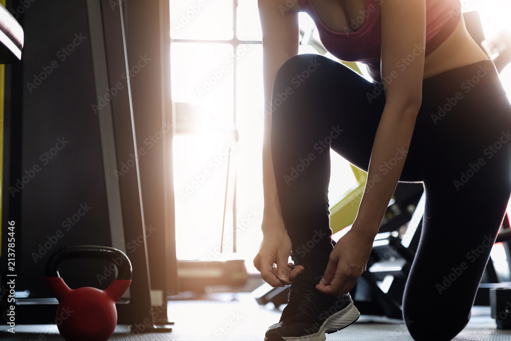 Sexy woman's hands tying shoelaces on sneakers in the gym - Fitness Gym Concept