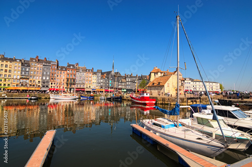 HONFLEUR, FRANCE-MAY 05, 2018: Yachts in the Honfleur harbor in a spring day. Color houses and their reflection in water. Ancient The Lieutenancy Building (Fr: La Lieutenance) at the background