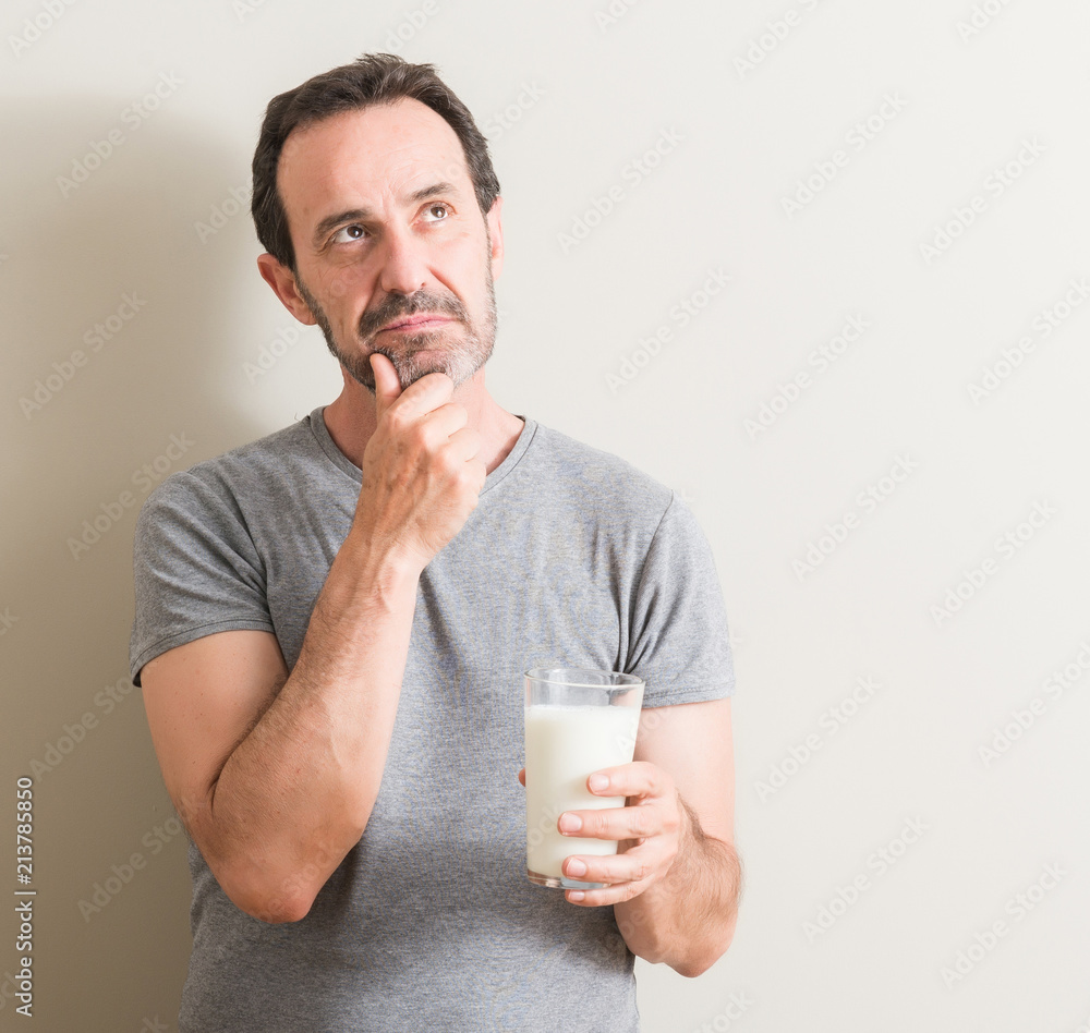 Senior man drinking a glass of milk serious face thinking about question, very confused idea Senior man drinking a glass of milk serious face thinking about question, very confused idea