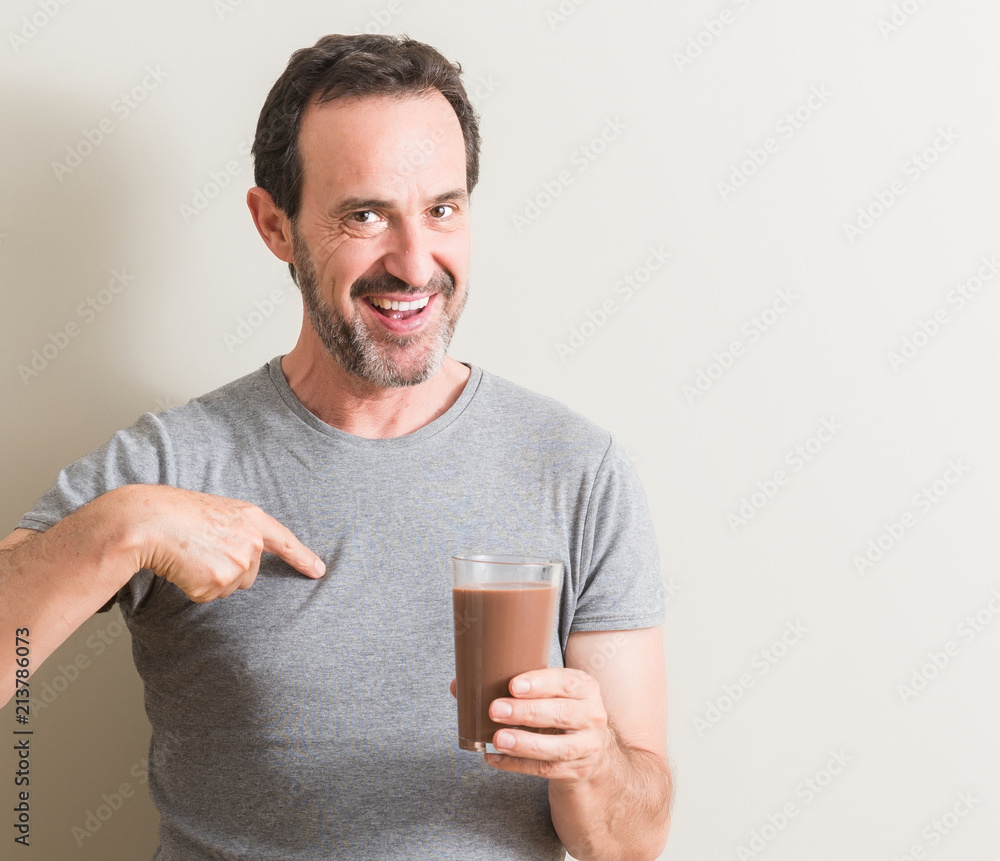 Senior man drinking chocolate milk shake with surprise face pointing finger to himself Senior man drinking chocolate milk shake with surprise face pointing finger to himself