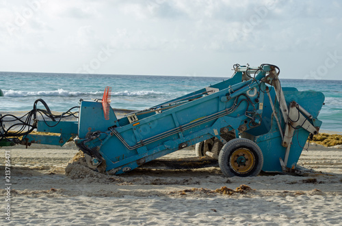 Tractor working at beach to clean sand. White, water