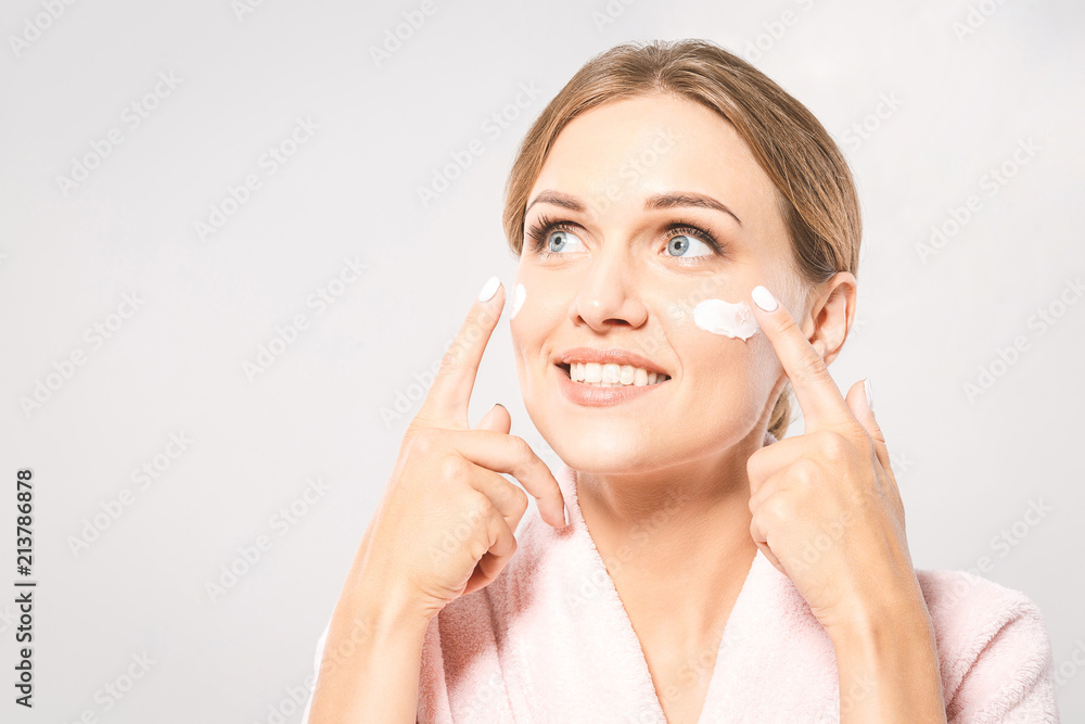 Portrait of young beautiful woman smiling while taking some facial cream isolated on white background with copy space. Portrait of young beautiful woman smiling while taking some facial cream isolated on white background with copy space.