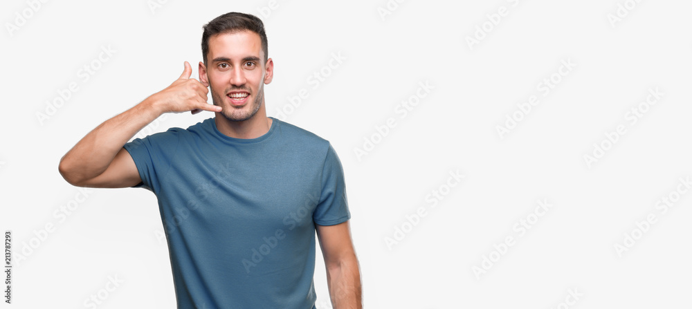 Naklejka premium Handsome young casual man smiling doing phone gesture with hand and fingers like talking on the telephone. Communicating concepts.