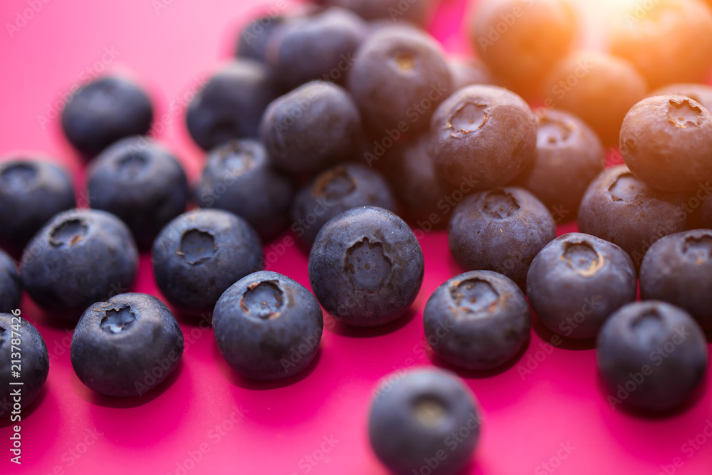 Close - up of ripe blueberries on a pink background in the sun, macro photo Close - up of ripe blueberries on a pink background in the sun, macro photo