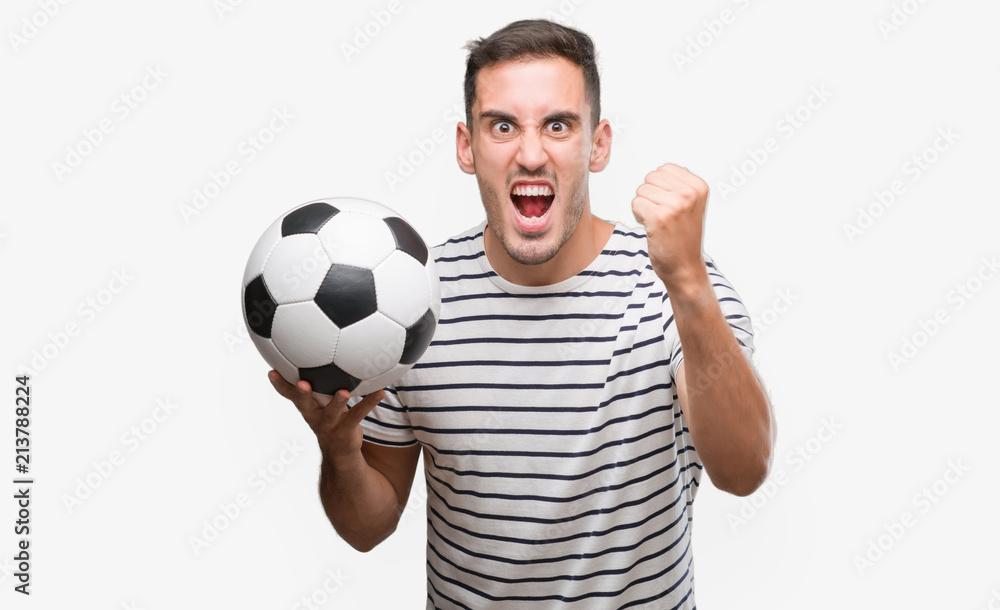 Handsome young man holding soccer football annoyed and frustrated shouting with anger, crazy and yelling with raised hand, anger concept Handsome young man holding soccer football annoyed and frustrated shouting with anger, crazy and yelling with raised hand, anger concept