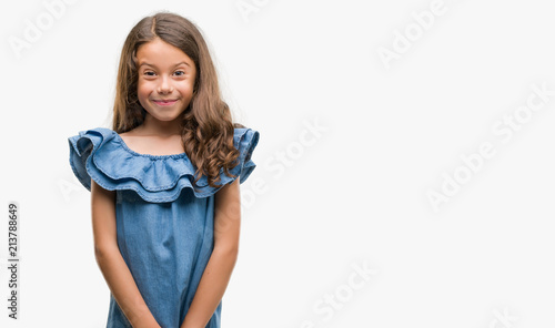 Brunette hispanic girl wearing denim dress with a happy face standing and smiling with a confident smile showing teeth