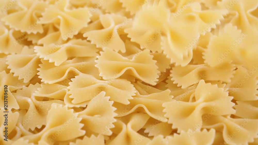 Food background, dried farfalle pasta falling on a heap, top view, slow motion Food background, dried farfalle pasta falling on a heap, top view, slow motion