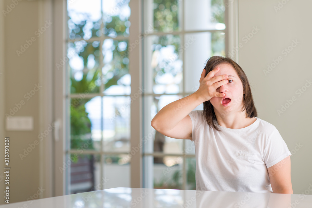 Down syndrome woman at home peeking in shock covering face and eyes with hand, looking through fingers with embarrassed expression. Down syndrome woman at home peeking in shock covering face and eyes with hand, looking through fingers with embarrassed expression.