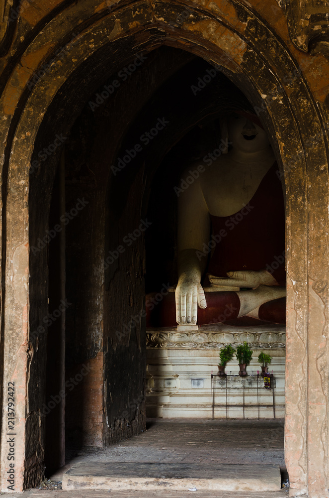 A larger than life statue of a sitting Buddha displays the touching Earth hand gesture, enclosed in a shrine in Bagan Temple Valley, Myanmar.