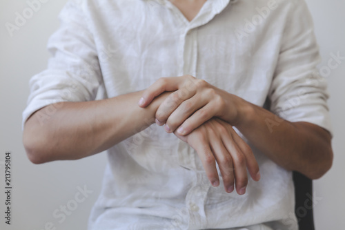 Closeup of young adult arms holding his painful wrist