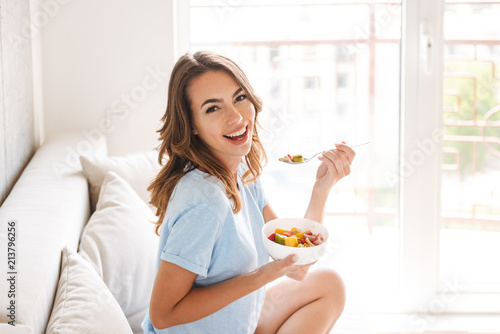 Cheerful young woman eating healthy breakfast