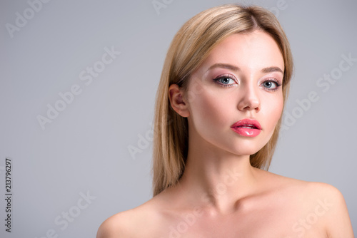 beautiful young blonde woman looking at camera isolated on grey