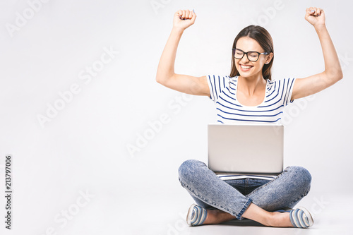 Business concept. Portrait of happy woman in casual sitting on floor in lotus pose and holding laptop isolated over white background. © denis_vermenko