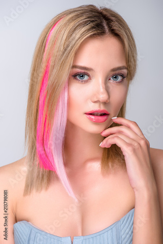 close-up portrait of beautiful young woman with colored hair strands isolated on grey