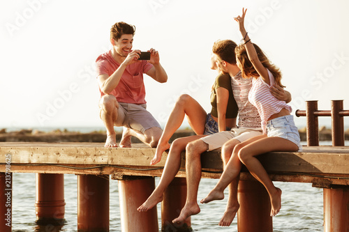 Friends sitting outdoors on the beach take a photo.