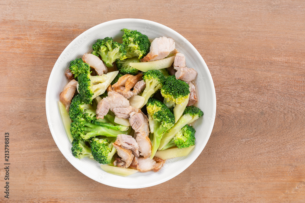 top view of stir fried pork belly and broccoli with soy sauce in a ceramic dish on wooden table. homemade style food concept. top view of stir fried pork belly and broccoli with soy sauce in a ceramic dish on wooden table. homemade style food concept.