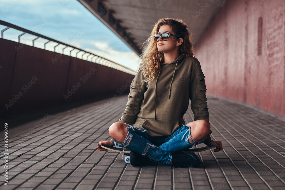 Portrait of a young woman in sunglasses dressed in a hoodie and