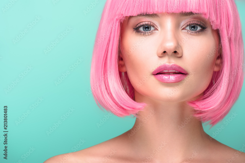 close-up portrait of young woman with pink bob cut looking at camera isolated on turquoise