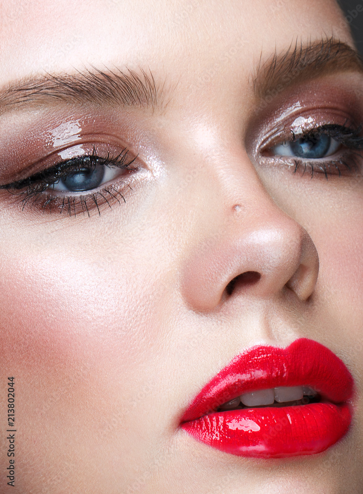 Close up portrait of beautiful young model with professional makeup, perfect skin. Trendy wet effect on the eyes and red lips