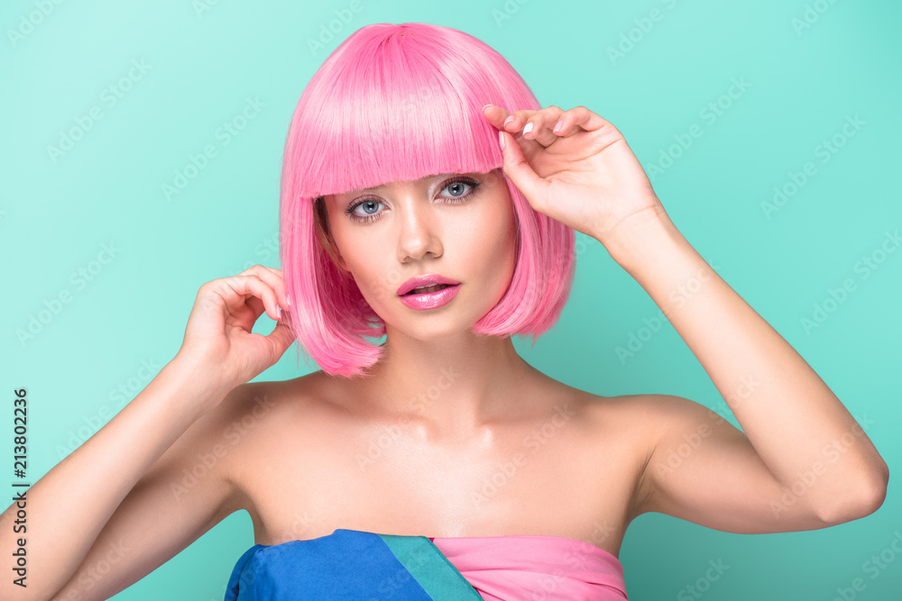sensual young woman with pink bob cut looking at camera isolated on turquoise