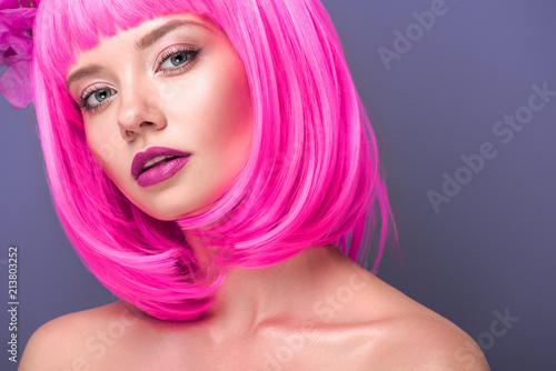 attractive young woman with pink bob cut looking at camera isolated on violet