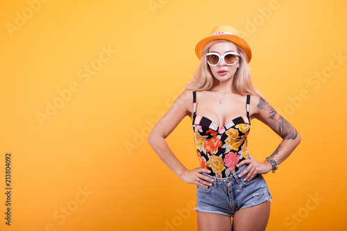 glamorous beautiful blond woman in sunglasses and hat over yellow background © DC Studio