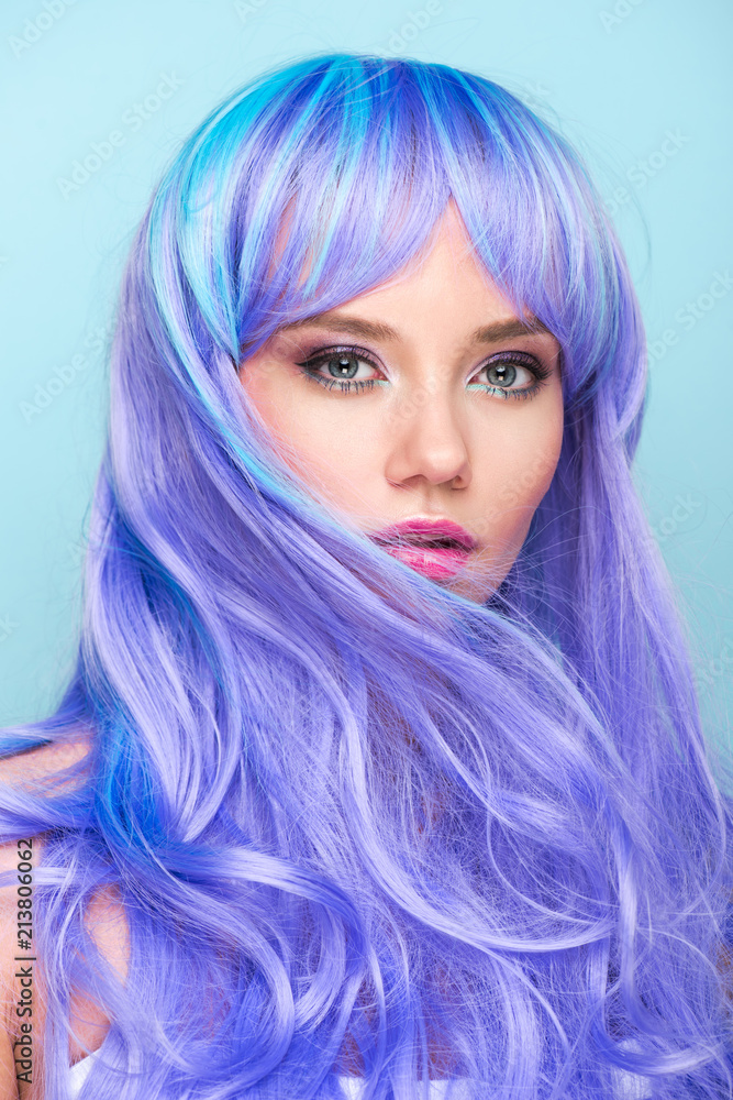 close-up portrait of beautiful young woman with curly blue hair looking at camera isolated on blue close-up portrait of beautiful young woman with curly blue hair looking at camera isolated on blue