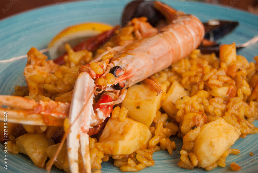 Paella in a light blue ceramic dish decorated by hand Paella in a light blue ceramic dish decorated by hand